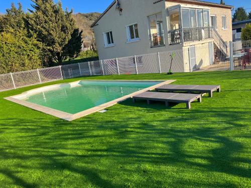 une piscine dans une cour avec deux bancs et une maison dans l'établissement Villa avec piscine dans Vallon Pont d’Arc, à Vallon-Pont-dʼArc
