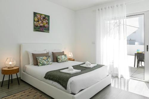 a white bedroom with a white bed and a window at Consolação Terrace in Consolacao