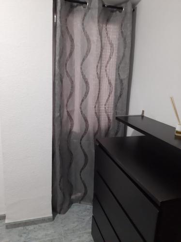 a black dresser in a room with a curtain at habitación grande en piso compartido con 2 adultos in Valencia