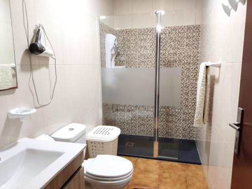 ein Bad mit einer Dusche, einem WC und einem Waschbecken in der Unterkunft 2 bedrooms house with sea view enclosed garden and wifi at Marinhas in Marinhas