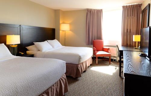 a hotel room with two beds and a chair at Rodd Grand Yarmouth in Yarmouth