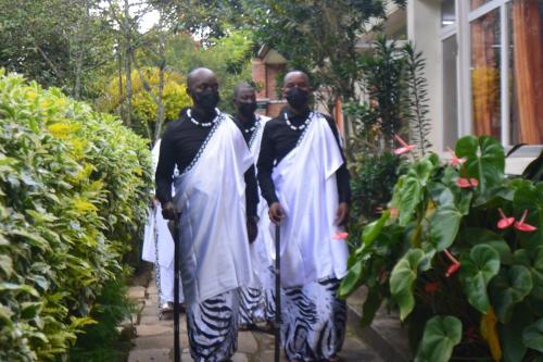 three men are walking down a sidewalk at Isange Paradise Resort in Ruhengeri
