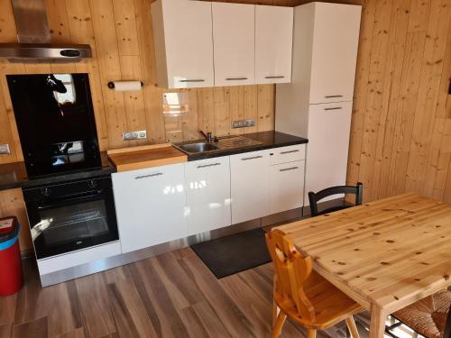une cuisine avec des armoires blanches et une table en bois dans l'établissement Le chalet du bois joli, à Kruth