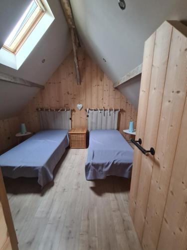 Cette chambre mansardée comprend 2 lits et une fenêtre. dans l'établissement Le chalet du bois joli, à Kruth