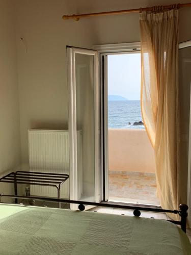 a bedroom with a window with a view of the ocean at ARETOUSA in Agia Pelagia Kythira