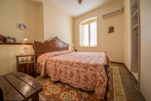 Schlafzimmer mit einem Bett mit einer roten Tagesdecke und einem Fenster in der Unterkunft Casa Anna in Carloforte