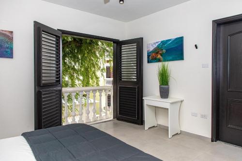 a bedroom with a bed and a balcony with a window at Zen Oceanfront Condo in Kralendijk