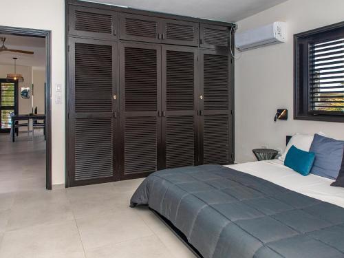 a bedroom with a large bed with wooden shutters at Zen Oceanfront Condo in Kralendijk