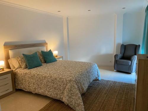 ein Schlafzimmer mit einem Bett und einem blauen Stuhl in der Unterkunft Combarro Suite in Combarro