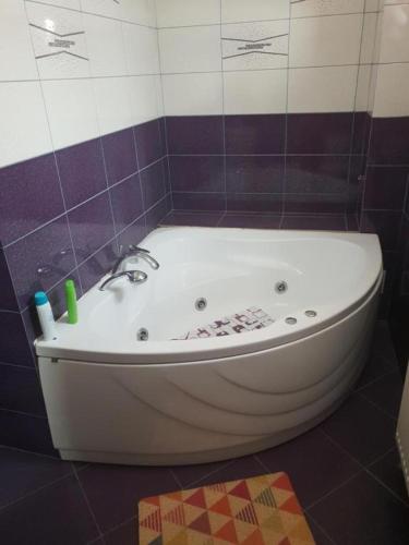a bath tub in a bathroom with purple and white tiles at La Zinculescu in Albeştii Pămînteni