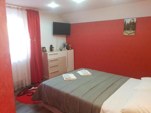 a bedroom with a red wall with a bed and a dresser at La Zinculescu in Albeştii Pămînteni