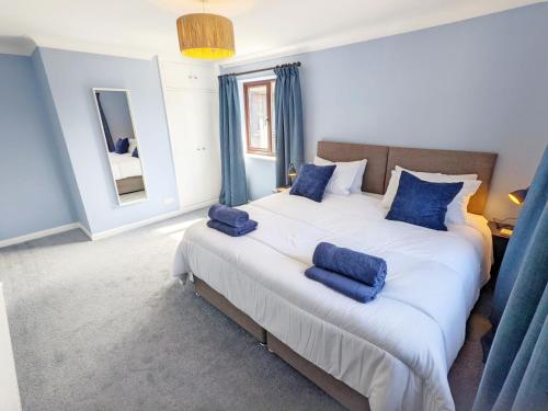a bedroom with a large bed with blue pillows on it at Three Jays in Emsworth