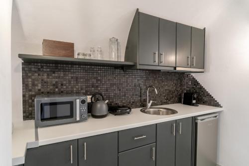 a kitchen with a sink and a microwave at Evanthia Best View Thirassia Island Hotel in Thirasia