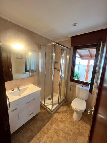 a bathroom with a toilet and a shower and a sink at Liencres tranquilo con piscina comunitaria in Liencres