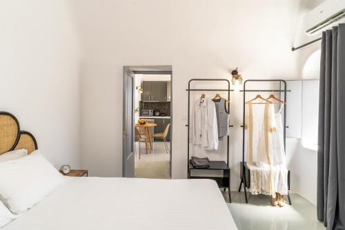 a bedroom with a white bed and a dress rack at Evanthia Best View Thirassia Island Hotel in Thirasia