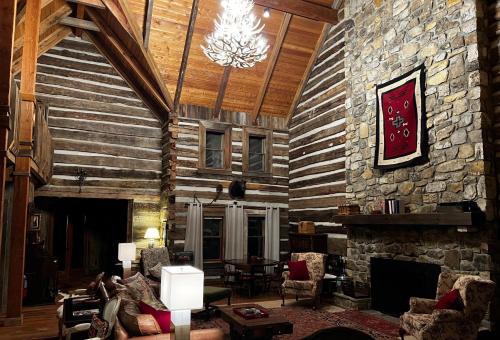 a living room with a stone fireplace and a chandelier at Altamont Lodge in Newland