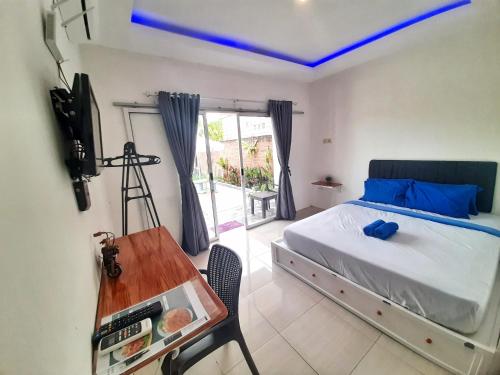 een slaapkamer met een bed en een tafel met een televisie bij Robiu Bed & Breakfast in Banyuwangi