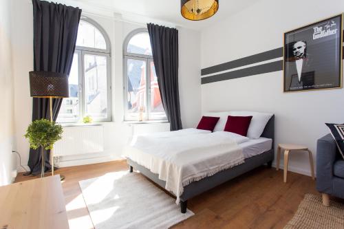 a bedroom with a bed and two windows at FULL HOUSE Apartment Hotel in Halle an der Saale