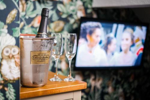 a bottle of wine in a bucket next to two wine glasses at Glen Wynne Windermere - FREE off-site Health Club access with Pool, Sauna, Steam Room & Gym Short 5 Minute Drive Away in Windermere