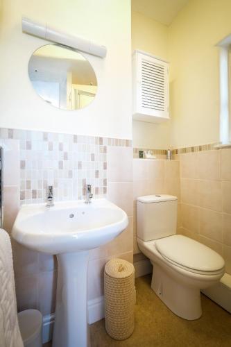 a bathroom with a sink and a toilet and a mirror at Glen Wynne Windermere - FREE off-site Health Club access with Pool, Sauna, Steam Room & Gym Short 5 Minute Drive Away in Windermere