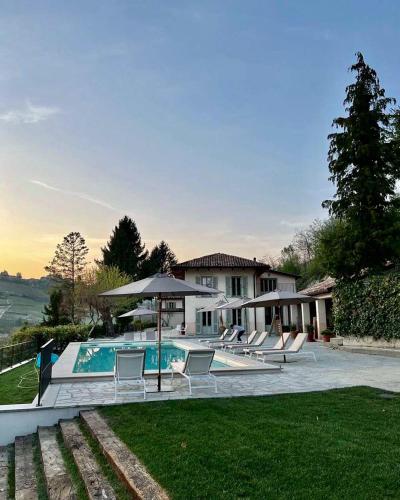 a pool with chairs and an umbrella and a house at Villa Giara in Calosso