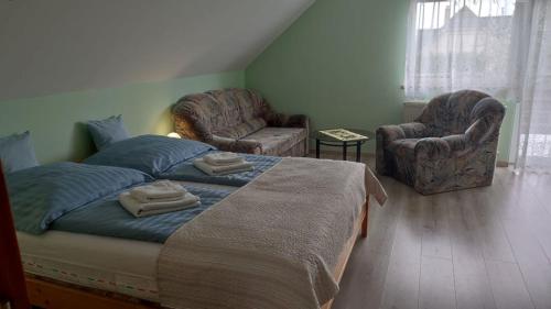 a bedroom with a bed and two chairs and a couch at Abigel Thermal Apartman in Bük