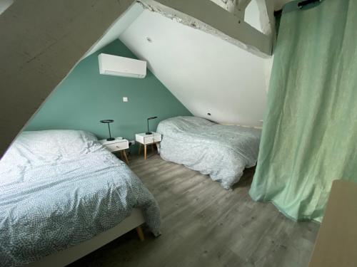 sypialnia na poddaszu z 2 łóżkami i niebieskimi ścianami w obiekcie Logement Loire climatisé, La Halte de Cuze, aux abords de la Loire a vélo w mieście Huismes