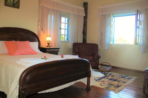 a bedroom with a bed and a chair and a window at Casa de Pedra, um refúgio para conhecer o Minho! in Ponte de Lima