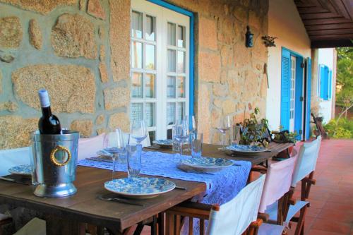 a wooden table with a bottle of wine on it at Casa de Pedra, um refúgio para conhecer o Minho! in Ponte de Lima