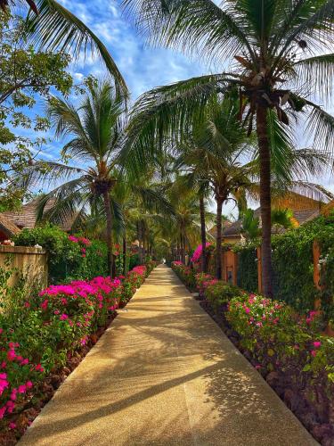 ein Weg mit Palmen und Blumen in einem Garten in der Unterkunft Agence Adjana Resort in Saly Portudal