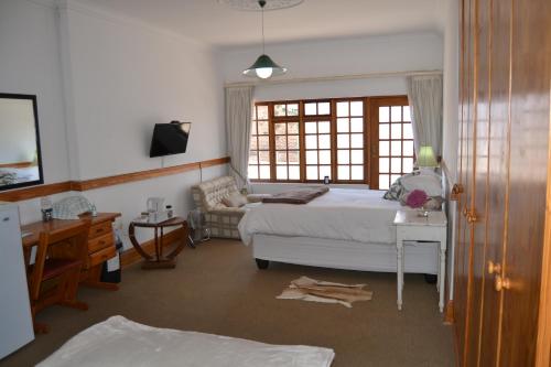 a bedroom with a bed and a desk and a window at Lekkerrus guesthouse in Krugersdorp