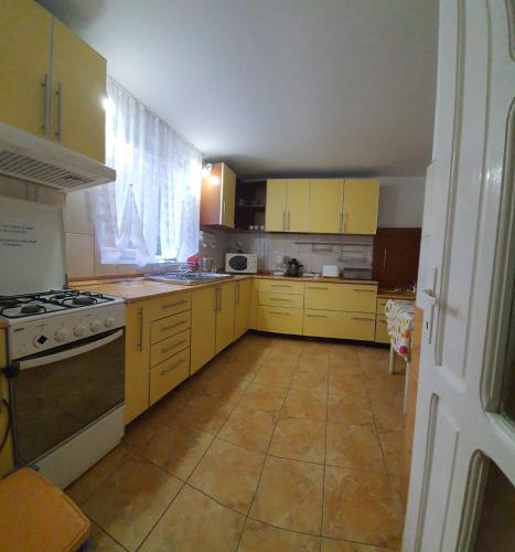 a kitchen with yellow cabinets and a stove top oven at Pensiunea Marydor in Gîrda de Sus