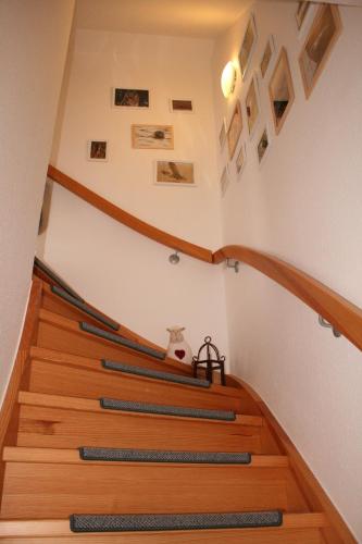 a staircase with wooden treads with pictures on the wall at Jensen-Huus in Dagebüll