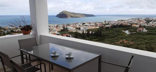 a white balcony with a table and chairs and the ocean at Thea Apartment in Agia Marina Nea Kydonias