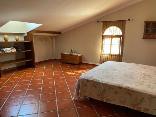 a bedroom with a bed and a window and a tiled floor at Casa Charo in Valle de Abdalagís