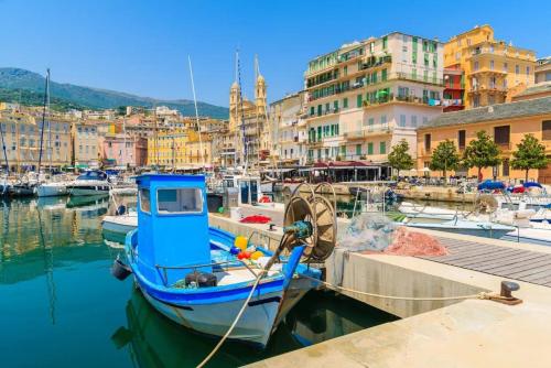 un barco azul está atracado en un puerto con edificios en Beau T2 sur le vieux port, centre de Bastia, en Bastia