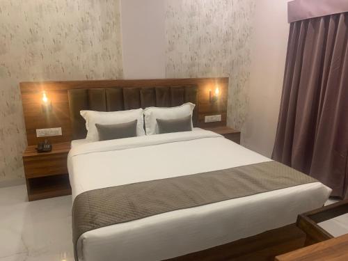a bedroom with a large bed with white sheets and pillows at Hotel Mumbai House-LIG Behind CHL Hospital in Indore