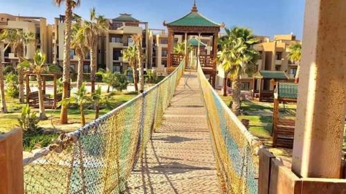 a bridge over a walkway with palm trees and buildings at Blue Bay Asia Sokhna Aqua park بلو باي اسيا العين السخنه - عائلات فقط in Ain Sokhna
