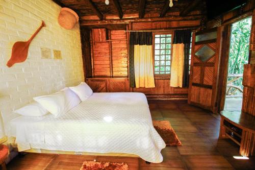 a bedroom with a white bed in a room with windows at Hosteria Flor de Canela in Puyo