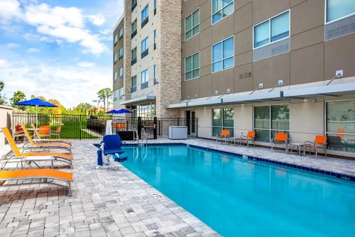 einen Pool mit Stühlen und ein Gebäude in der Unterkunft Holiday Inn Express & Suites Sanford - Lake Mary, an IHG Hotel in Sanford