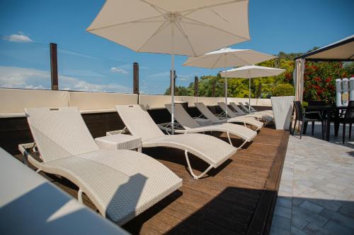 une rangée de chaises et de parasols blancs sur un toit dans l'établissement Resort Casino di Caccia, à Custoza