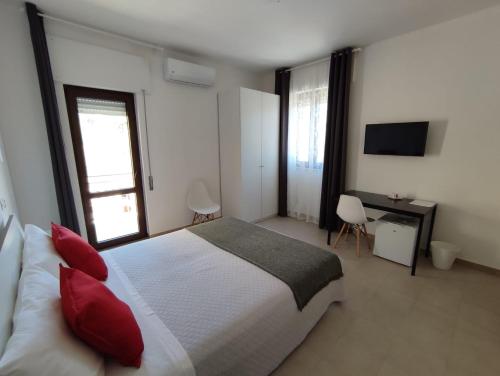 a bedroom with a bed with red pillows and a desk at Cristian Rooms in Avola