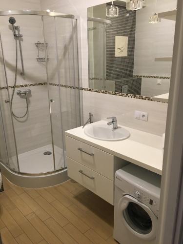 a bathroom with a shower and a sink and a washing machine at Bursztynowy 1 in Karwia