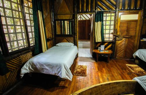 a bedroom with a bed in a room with windows at Hosteria Flor de Canela in Puyo