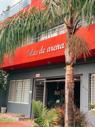 una palmera frente a un edificio con un cartel en Islas de Arena en Colón