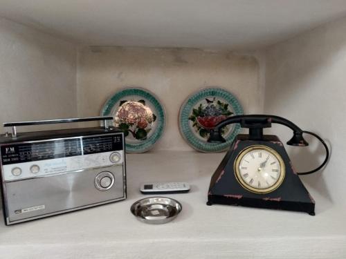 a radio and a clock on a counter next to a microwave at Mèna Mè - Casa vacanza - Salento in Parabita