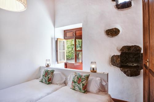 Hotelito Rural Flor de Timanfaya في تيناجون: غرفة بيضاء مع أريكة ونافذة