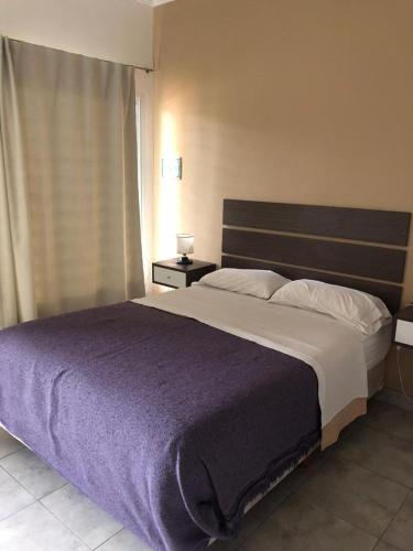 1 dormitorio con 1 cama grande con manta morada en Islas de Arena en Colón