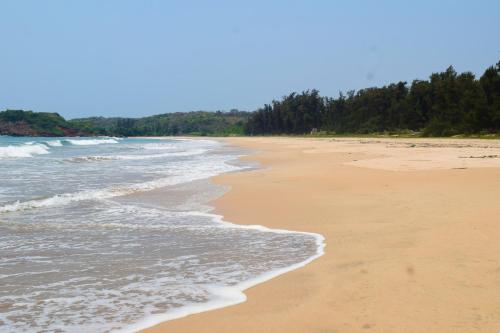 an empty beach with trees in the background at Rama Niwas Beach Home Stay in Pawas