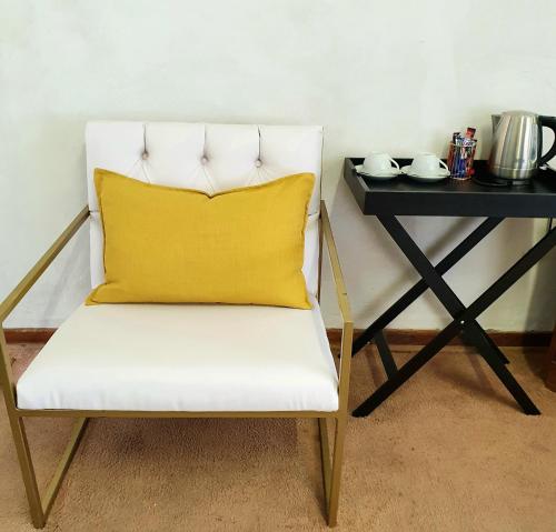 a white chair with a yellow pillow next to a table at XG Guesthouse in Barkly East